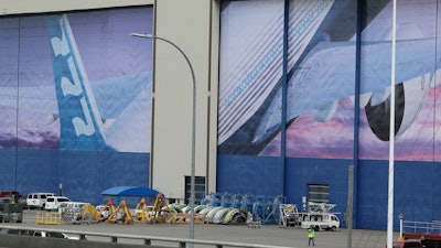 A worker walks near a mural of a Boeing 777 airplane at the company's manufacturing facility in Everett, Wash., March 23, 2020.