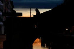 A woman wearing a face mask checks her phone as she walks at the Naviglio Grande canal in Milan, March 10, 2020.