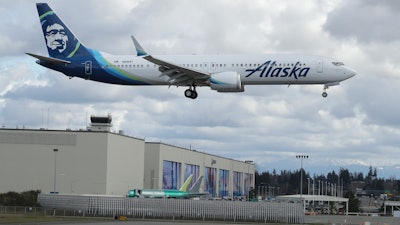 An Alaska Airlines Boeing 737-9 Max flies over Boeing's manufacturing facility in Everett, Wash., March 23, 2020.