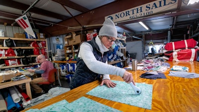 Karen Haley cuts cotton fabric at the North Sails shop in Freeport, Maine, March 23, 2020.