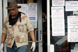 An employees stands at the entrance to a gun shop in Culver City, Calif., March 24, 2020.