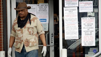 An employees stands at the entrance to a gun shop in Culver City, Calif., March 24, 2020.