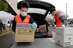Volunteers Keshia Link, left, and Dan Peterson unload boxes of donated gloves and alcohol wipes at the University of Washington, March 24, 2020.