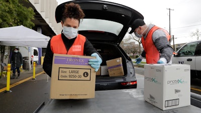 Volunteers Keshia Link, left, and Dan Peterson unload boxes of donated gloves and alcohol wipes at the University of Washington, March 24, 2020.