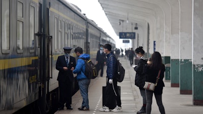 Passengers board a train at the Jingmen Railway Station in Jingmen, China, March 25, 2020.