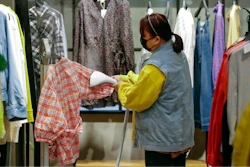 A worker wearing a protective face mask irons clothes at a re-opened shopping mall in in Wuhan, March 30, 2020.