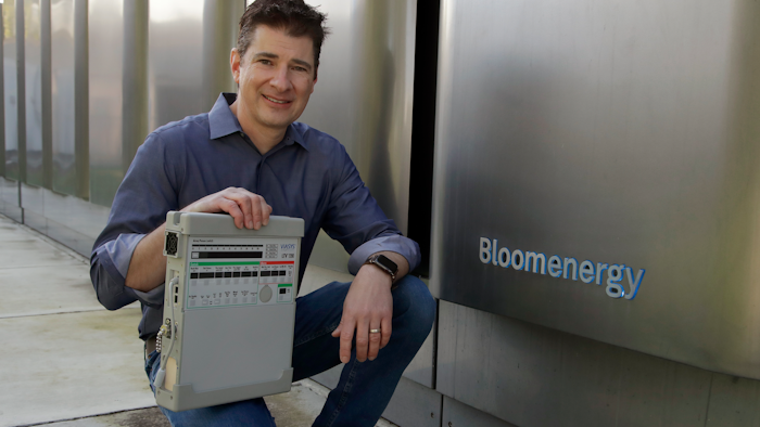 Joe Tavi, Bloom Energy's senior director of manufacturing, holds a refurbished ventilator beside the company's fuel cells, April 1, 2020, in Sunnyvale, Calif.