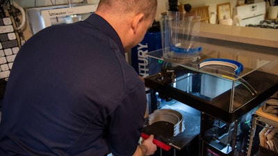Master Sgt. Justin Pittman, Innovation Lab senior project manager, removes newly printed face shield headbands from a 3D printer, April 7, 2020, Dover Air Force Base, Del.