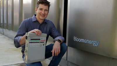 Joe Tavi, Bloom Energy's senior director of manufacturing, holds a refurbished ventilator beside the company's fuel cells, April 1, 2020, in Sunnyvale, Calif.