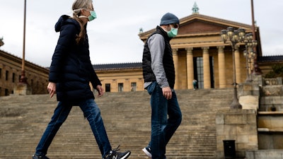 A couple in protective masks walk past the Philadelphia Museum of Art, April 3, 2020.
