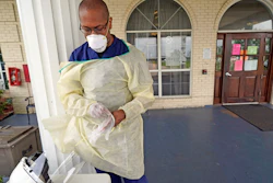 Dr. Robin Armstrong puts on gloves outside the entrance to The Resort nursing home, Texas City, Texas, April 7, 2020.