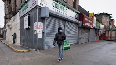 A woman walks by closed stores in New York, April 3, 2020.