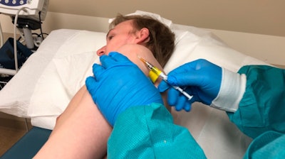 A participant in a COVID-19 vaccine trial receives an injection in Kansas City, Mo., April 8, 2020.