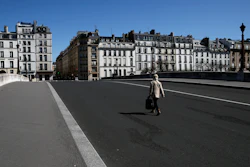 A woman crosses an empty bridge in Paris, April 14, 2020.