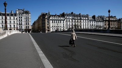 A woman crosses an empty bridge in Paris, April 14, 2020.