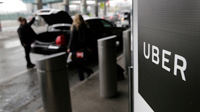 In this March 15, 2017, file photo, a sign marks a pick-up point for the Uber car service at LaGuardia Airport in New York. The New York Times and other media are reporting Sunday, June 11, 2017, that Uber's board is considering placing Kalanick, the CEO of the ride-hailing company, on leave.