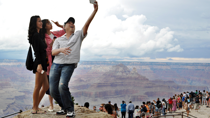 Tourists Joseph Lin, Ning Chao, center, and Linda Wang, left, pose along the south rim at Grand Canyon National Park, Ariz., Aug. 2, 2015.