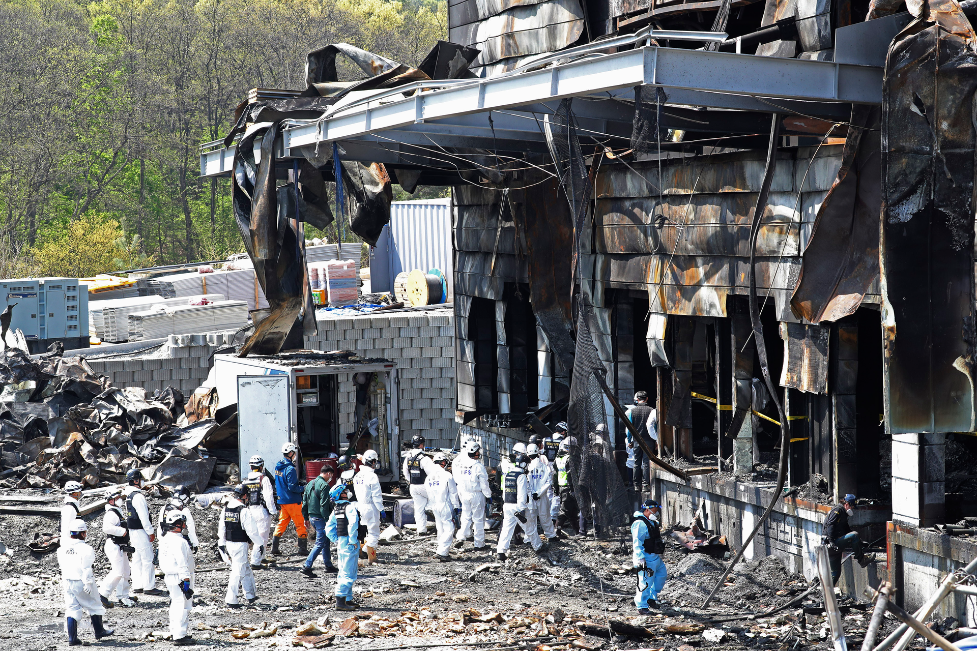 Police investigators enter to inspect a burnt construction site.