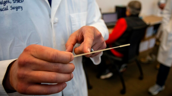 In this Tuesday, April 28, 2020, photo, Alexander Faigen, of Augusta University's Dental College of Georgia, shows how far a nasal swab must be inserted in Augusta, Ga. Volunteers at a Georgia dental college who started using a 3D printer to make nasal swabs used in test kits for the coronavirus are now a major part of the state's effort to expand testing.