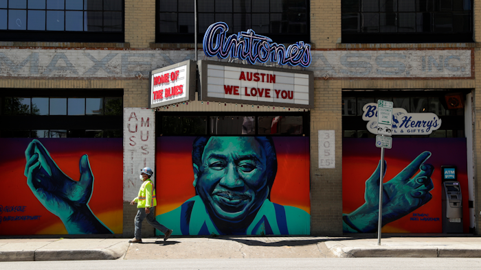 A worker passes a closed nightclub in Austin, Texas, May 18, 2020.