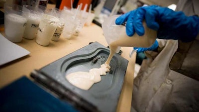 A student pouring polyurethane into a flip-flop mold.