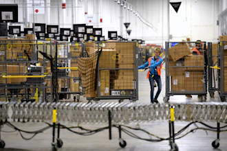 Associates move bins filled with products at the loading dock of Amazon's fulfillment center in Livonia, Mich., March 23, 2018.