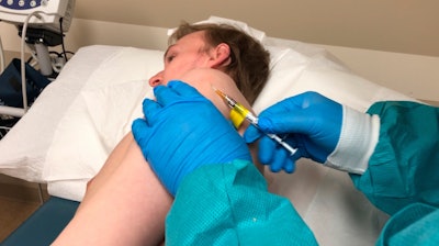 A participant in a COVID-19 vaccine trial receives an injection in Kansas City, Mo., April 8, 2020.