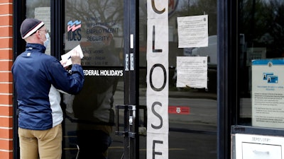 A man writes information in front of Illinois Department of Employment Security in Chicago, April 30, 2020.