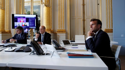 French President Emmanuel Macron, right, and Foreign Minister Jean-Yves le Drian, center, during an international videoconference on vaccination at the Elysee Palace in Paris, May 4, 2020.