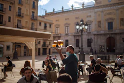 A waiter carries beers for customers sitting on a terrace bar in Tarragona, Spain, May 11, 2020.