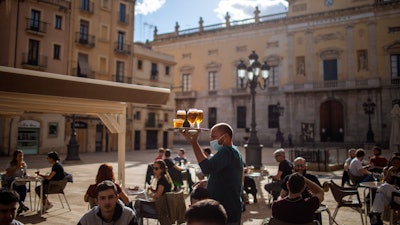 A waiter carries beers for customers sitting on a terrace bar in Tarragona, Spain, May 11, 2020.