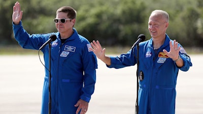 NASA astronauts Bob Behnken, left, and Doug Hurley wave as they leave a news conference at the Kennedy Space Center in Cape Canaveral, Fla., May 20, 2020.
