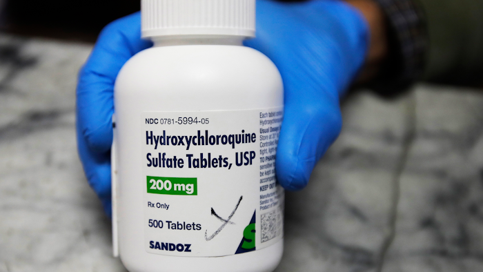 A pharmacist holds a bottle of hydroxychloroquine in Oakland, Calif., April 6, 2020.