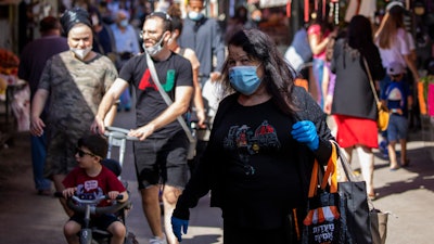 People wearing masks visit a food market in Tel Aviv, May 7, 2020.