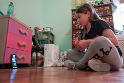 Elena Moretti, 11, looks at her cellphone as she prepares to attend an online dancing lesson in her bedroom in Rome, May 14, 2020.