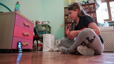 Elena Moretti, 11, looks at her cellphone as she prepares to attend an online dancing lesson in her bedroom in Rome, May 14, 2020.