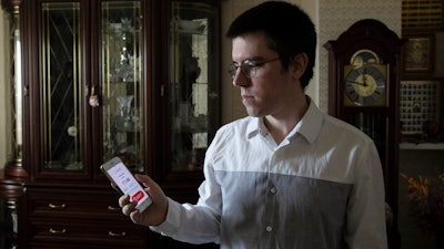 Vladimir Perevalov shows a Social Monitoring app installed on his phone in his apartment in Shcherbinka, outside Moscow, May 27, 2020.