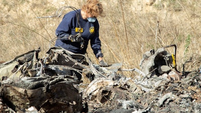 NTSB investigator Carol Hogan examines wreckage as part of the investigation of a helicopter crash near Calabasas, Calif., that killed former NBA player Kobe Bryant, his 13-year-old daughter, Gianna, and seven others, Jan. 27, 2020.