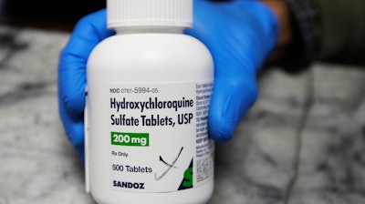 A pharmacist holds a bottle of hydroxychloroquine in Oakland, Calif., April 6, 2020.