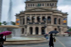 Women walk past the Old Opera in Frankfurt during heavy rain, June 4, 2020.