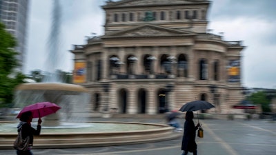 Women walk past the Old Opera in Frankfurt during heavy rain, June 4, 2020.