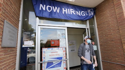 A customer walks out of a U.S. Post Office branch advertising a job opening, Seattle, June 4, 2020.