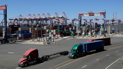 Trucks travel along a loading dock at the Port of Long Beach in Long Beach, Calif., Aug. 22, 2018.