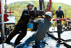 Workers move a section of well casing into place at a Chesapeake Energy natural gas well.