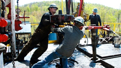 Workers move a section of well casing into place at a Chesapeake Energy natural gas well.