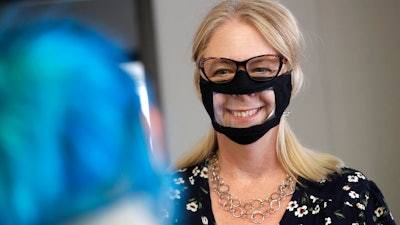 In this June 3, 2020, photo, Chris LaZich, of Fleet Science Center, wears a mask with a window as she talks with Delpha Hanson in San Diego. Face coverings to curb the spread of the coronavirus are making it hard for people who read lips to communicate. That has spurred a slew of startups making masks with plastic windows to show one's mouth. The companies are getting inundated with orders from family and friends of deaf people, people helping English learners see the pronunciation of words, and even hospitals that want their patients to be able to see smiles.