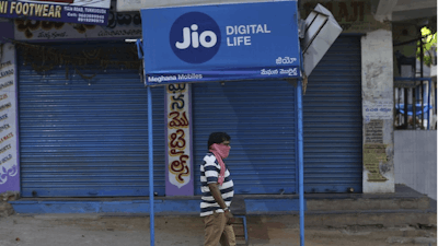 A man walks past a Reliance Jio sign in front of a closed shop in Hyderabad, India, April 22, 2020.