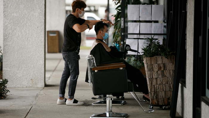 Hairstylist Travis Vu gives a haircut to Minh Dao at his outdoor hair salon in Fountain Valley, Calif., July 22, 2020.