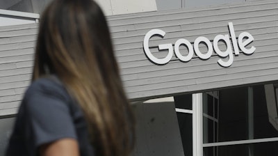 A woman walks below a Google sign on its campus in Mountain View, Calif., Sept. 24, 2019.