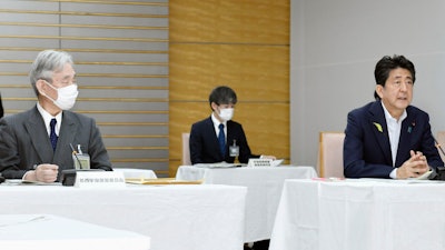 Japanese Prime Minister Shinzo Abe, right, at a government meeting on space development at his office in Tokyo, June 29, 2020.